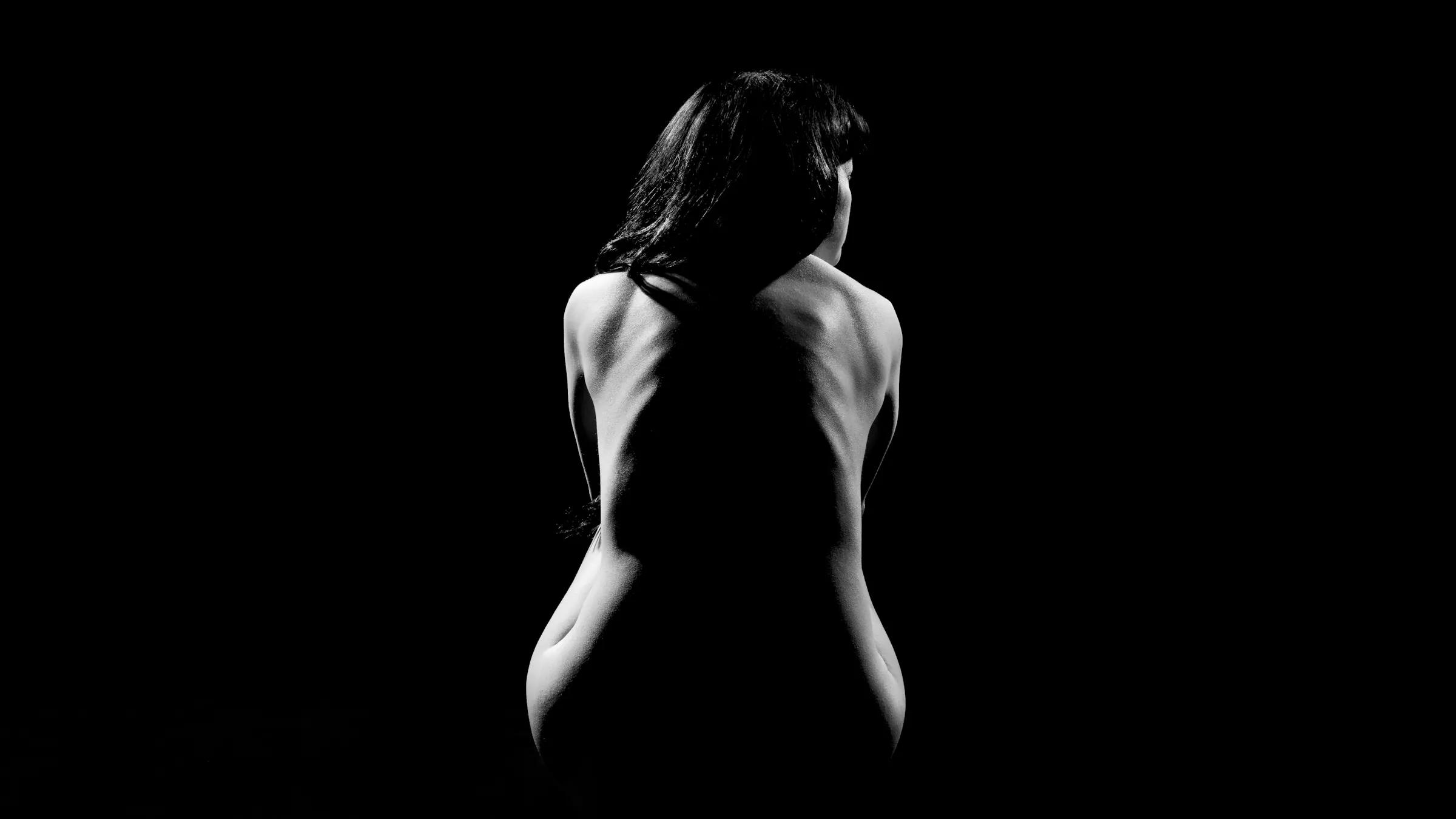 Silhouette einer Frau im Dunkeln, seitlich vom Licht umrissen